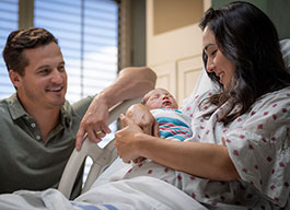 Photo of a couple smiling at their new baby.